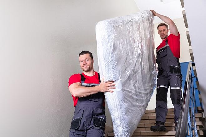 heavy lifting as box spring is removed for disposal in Byron